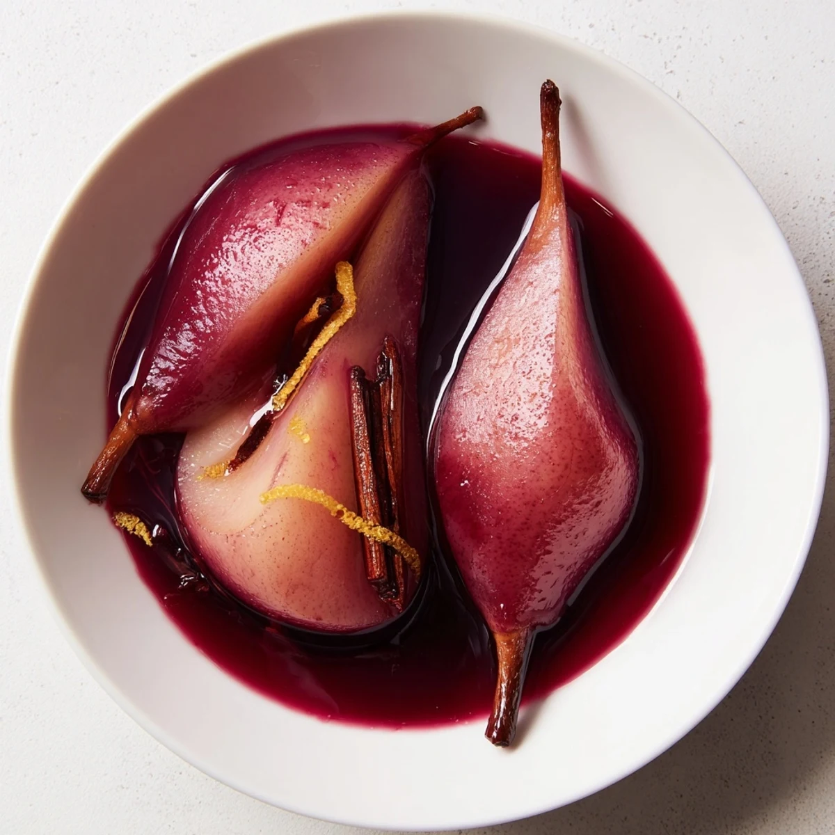 Soft, fragrant Pears in Grape Juice, poached in a sweet, aromatic liquid and presented alongside a delicate drizzle of reduced syrup.