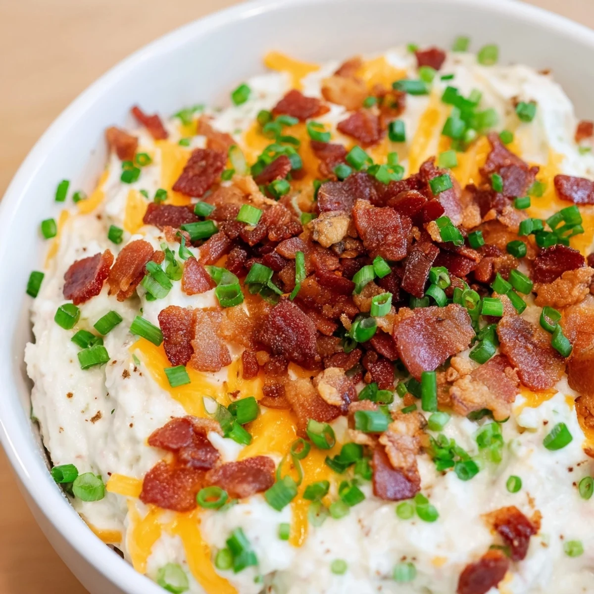 A party platter showcases Loaded Baked Potato Dip garnished with bacon and chives, surrounded by golden, crunchy potato chips ready to scoop.