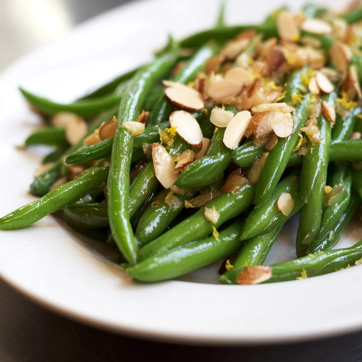 Green Beans with Toasted Almonds and Lemon garnished with lemon wedges, served warm alongside grilled chicken.