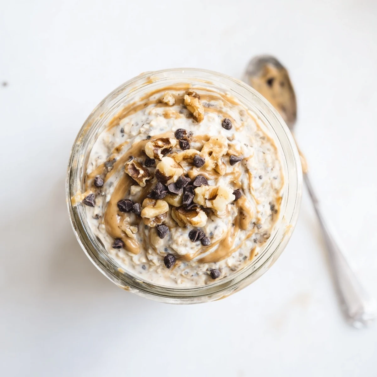 A jar of Cookie Dough Overnight Oats with creamy oats, chocolate chips, and a walnut topping for a hearty breakfast.