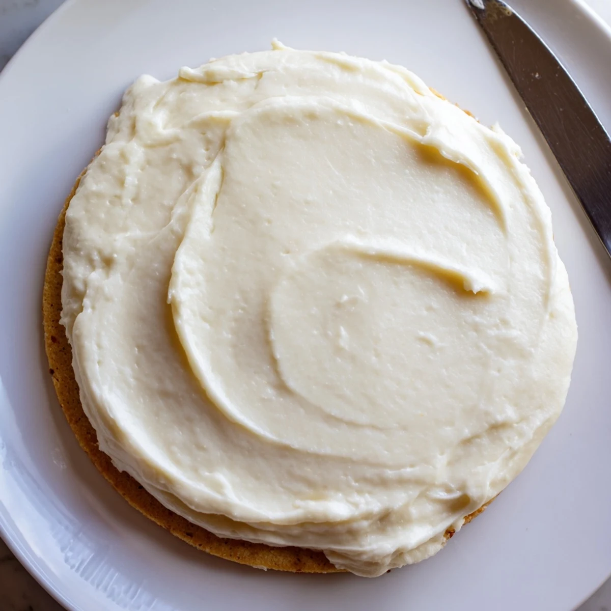 Homemade Easy Sugar Cookie Frosting in a mixing bowl with a spatula, showcasing its creamy and spreadable texture.