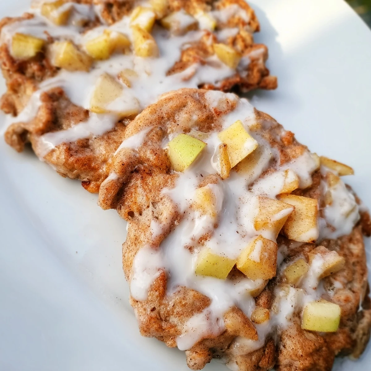 Apple Fritter Pancakes are golden and fluffy, studded with tender apples and dusted with powdered sugar glaze on a cozy plate.