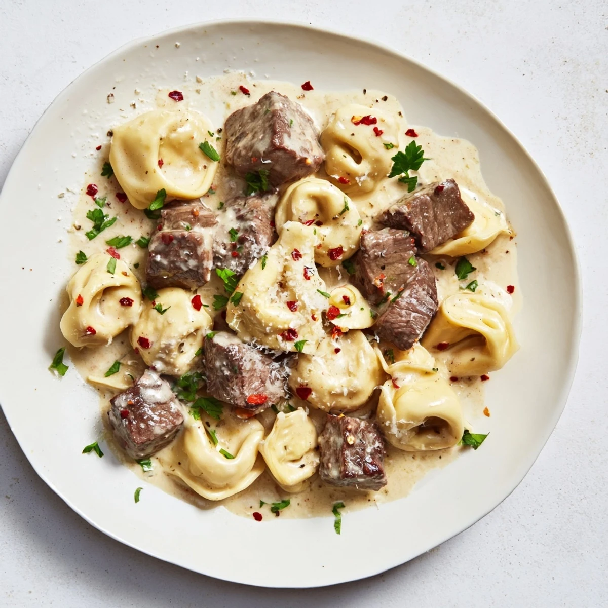 Savory Garlic Steak Tortellini tossed in a luscious garlicky sauce, served hot with a side salad suggestion.
