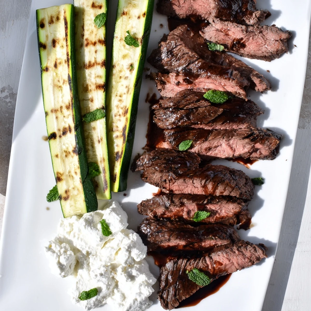 Juicy balsamic marinated flank steak with smoky grilled zucchini and creamy whipped feta served on a rustic platter.