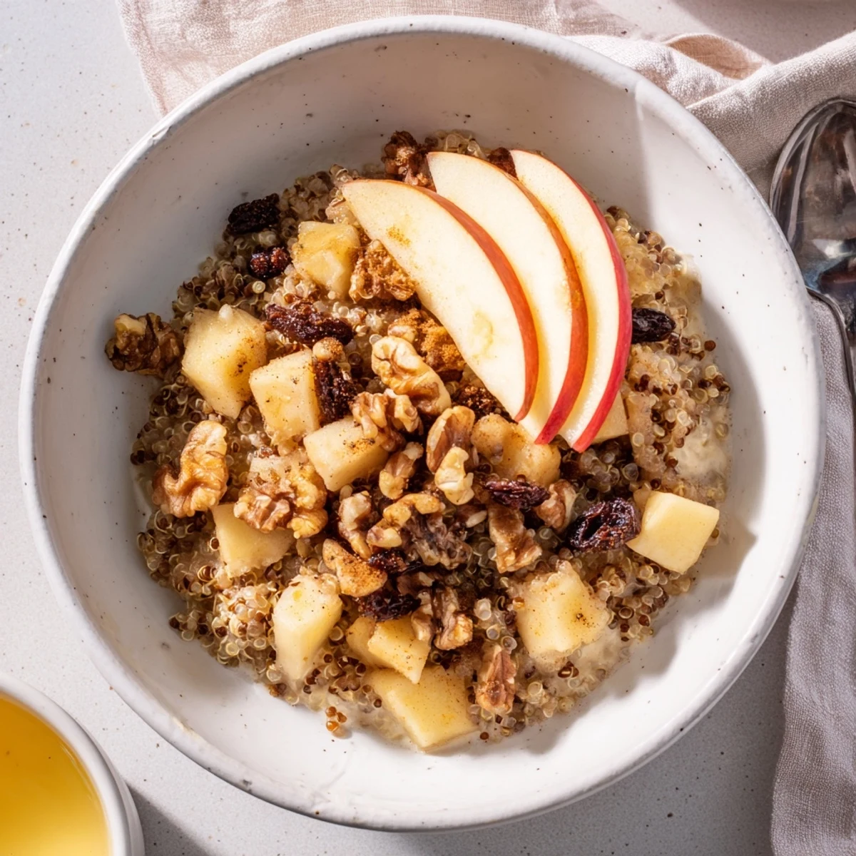 Fluffy warm Healthy Quinoa Apple Breakfast bowl topped with crunchy walnuts and a drizzle of honey.