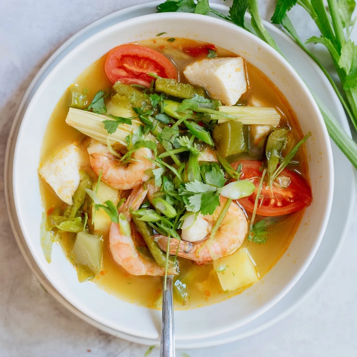 Ladle of Canh Chua with fish, tamarind broth, bean sprouts, and cilantro garnish.