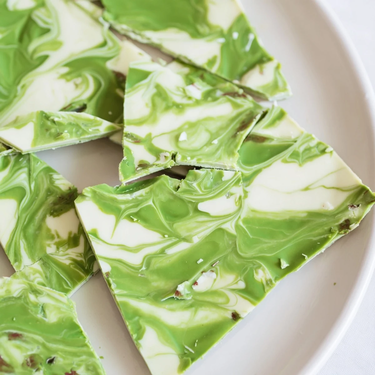 A close-up of a festive Matcha Peppermint Bark slice showcasing its marbled texture and sweet, minty aroma.