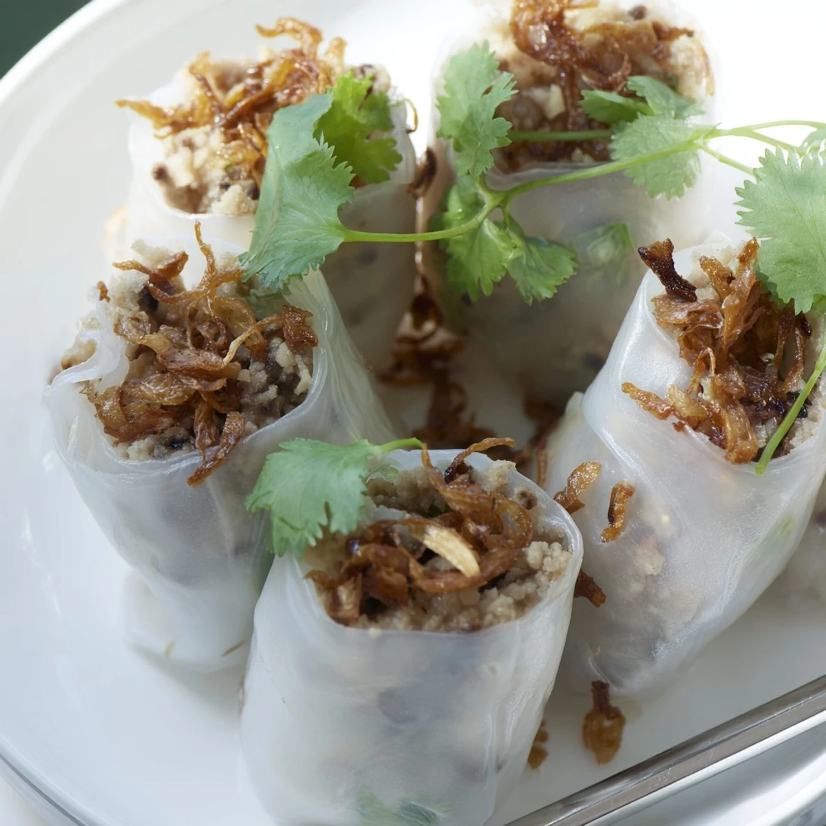 A close-up of Banh Cuon with bean sprouts, cucumber, and a small bowl of tangy nuoc cham dipping sauce.