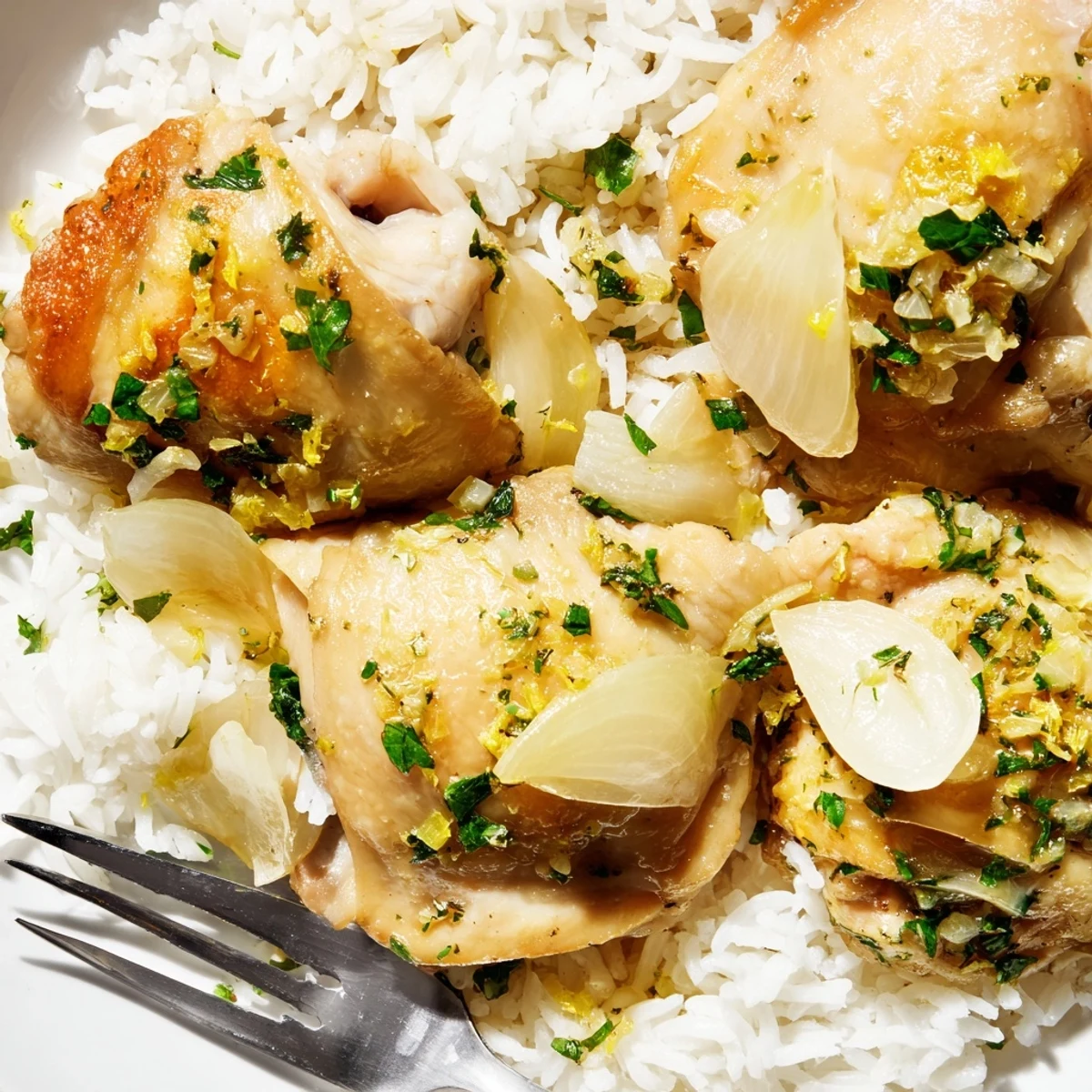 Golden slow cooker lemon herb chicken pieces resting on a bed of fluffy white rice