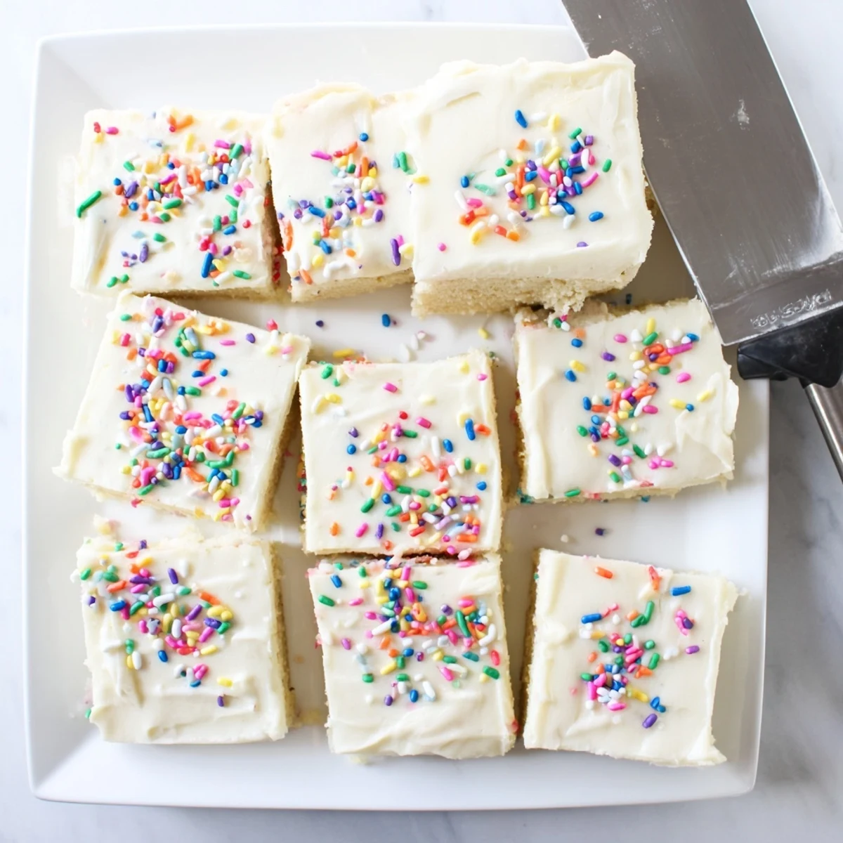 Golden sugar cookie bars spread with creamy buttercream frosting and festive holiday sprinkles