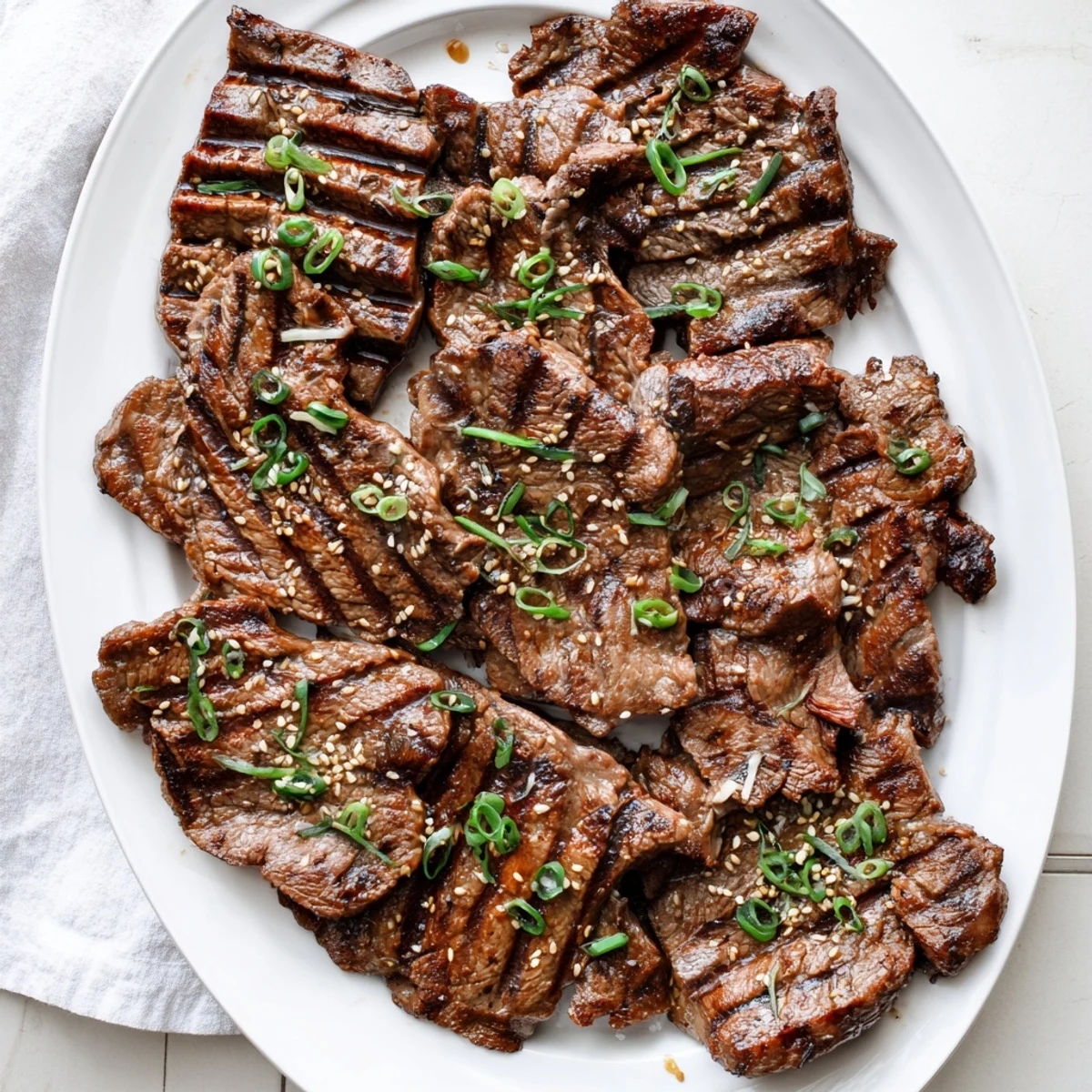 Juicy flanken-cut Korean Galbi beef ribs arranged on serving platter with toasted sesame seed sprinkle