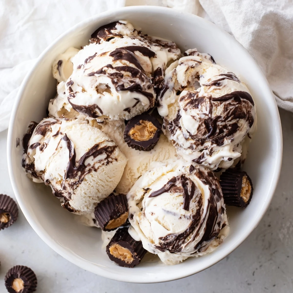 Creamy homemade moose tracks ice cream with fudge swirls and peanut butter cup pieces scooped into a serving bowl