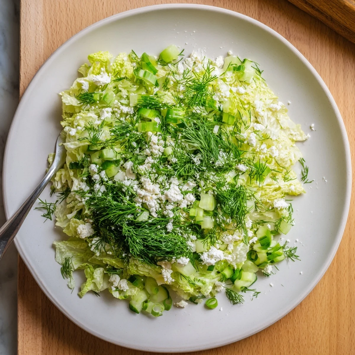 Vibrant bowl of Maroulosalata featuring crisp lettuce, scallions, mint, dill, and olive oil emulsion