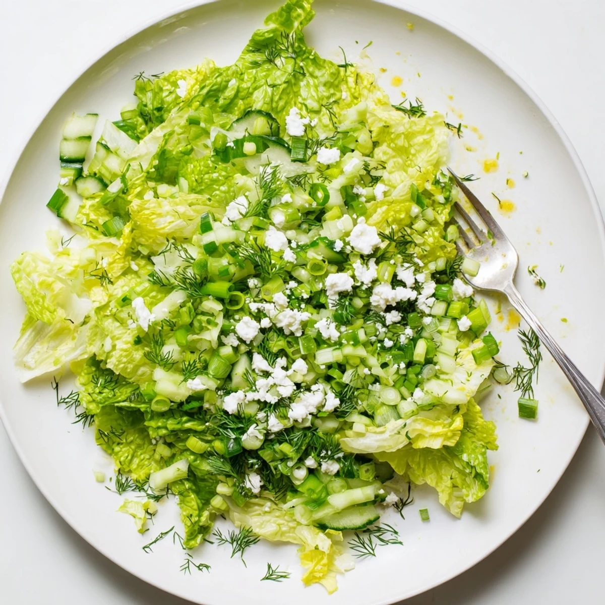 Traditional Maroulosalata topped with crumbled feta, cucumbers, and aromatic fresh herbs in a serving bowl