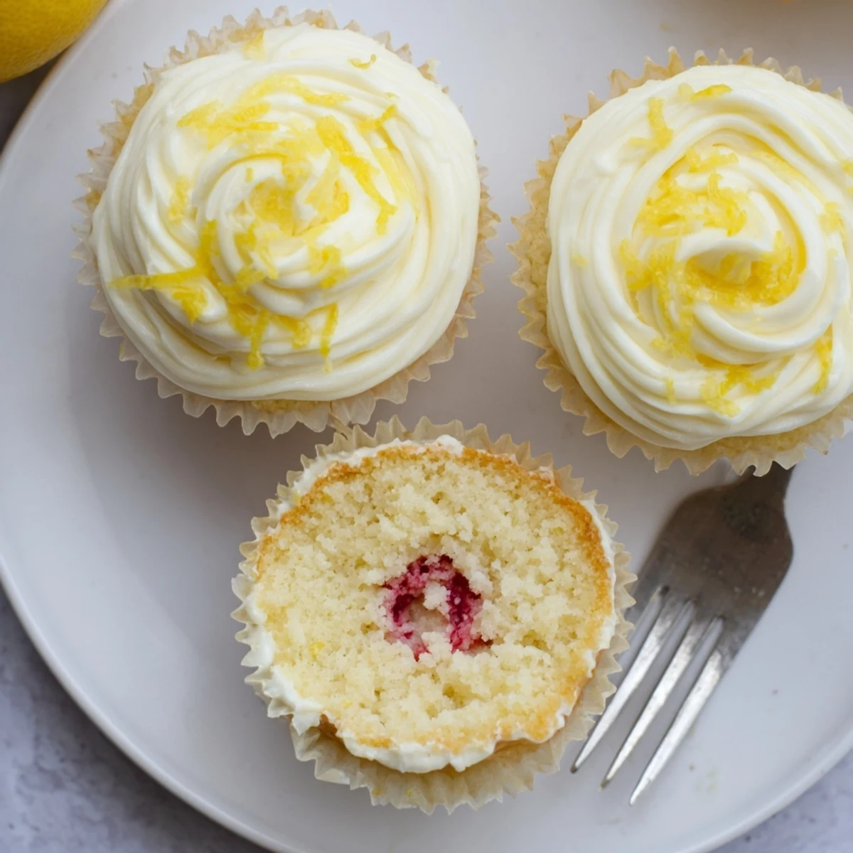 Zesty lemon cupcakes featuring hidden raspberry filling and creamy lemon icing for spring desserts