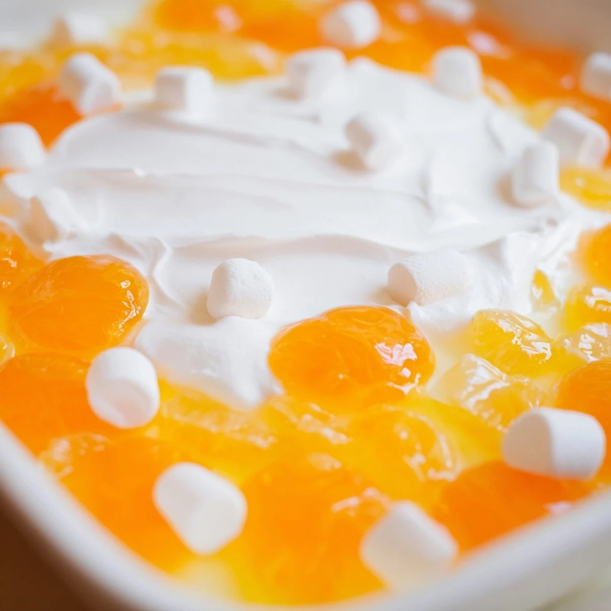 Creamy Easter Orange Jello Salad showcasing vibrant orange color set in a decorative bowl with white fluffy topping