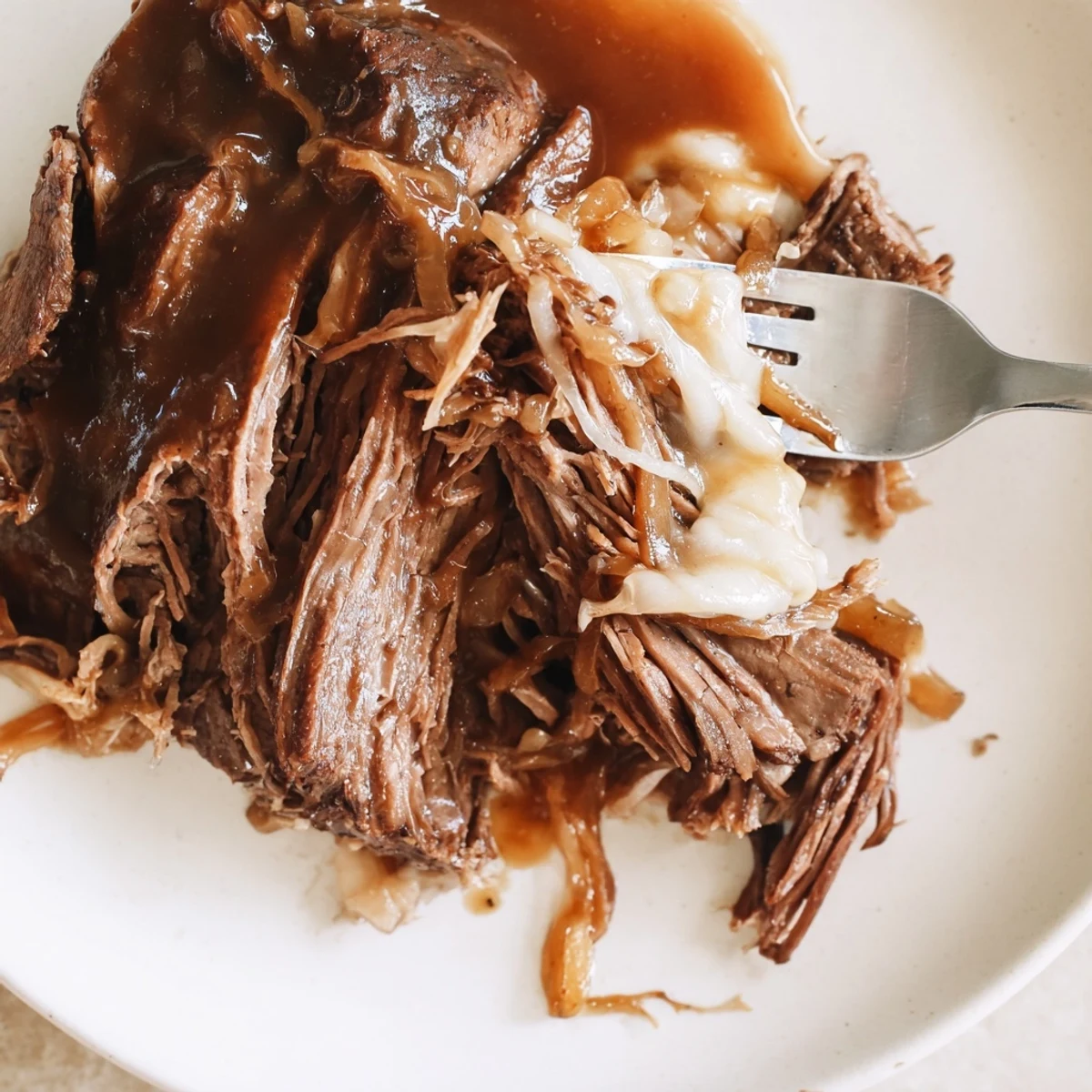 Tender French onion pot roast with caramelized onions, baby potatoes, and carrots in rich gravy