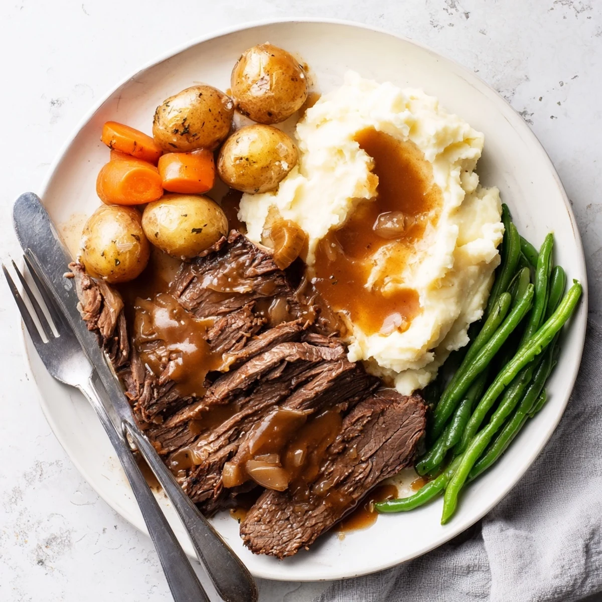 Golden brown Southern style pot roast plate with tender beef slices, rich gravy, mashed potatoes and green beans