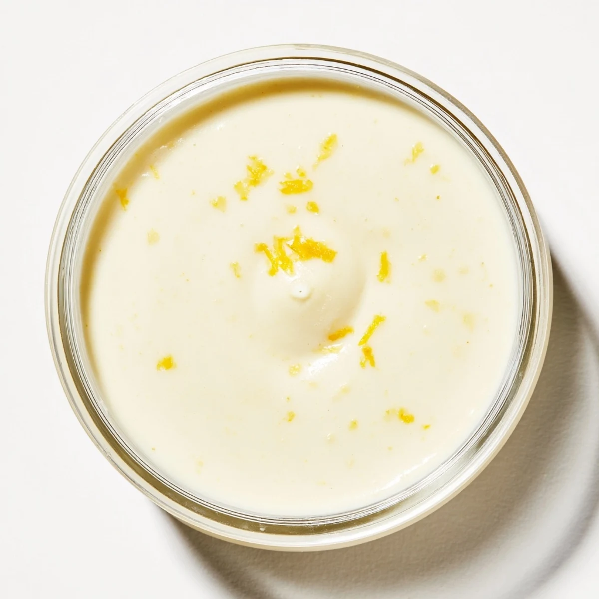 Silky smooth lemon posset dessert topped with lemon zest and shortbread cookie