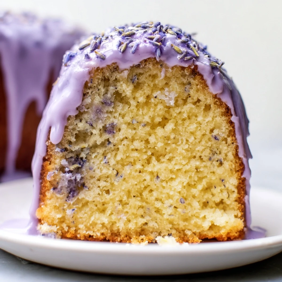 Lavender cake with lemon glaze drizzled over a tender golden crumb scattered with purple buds