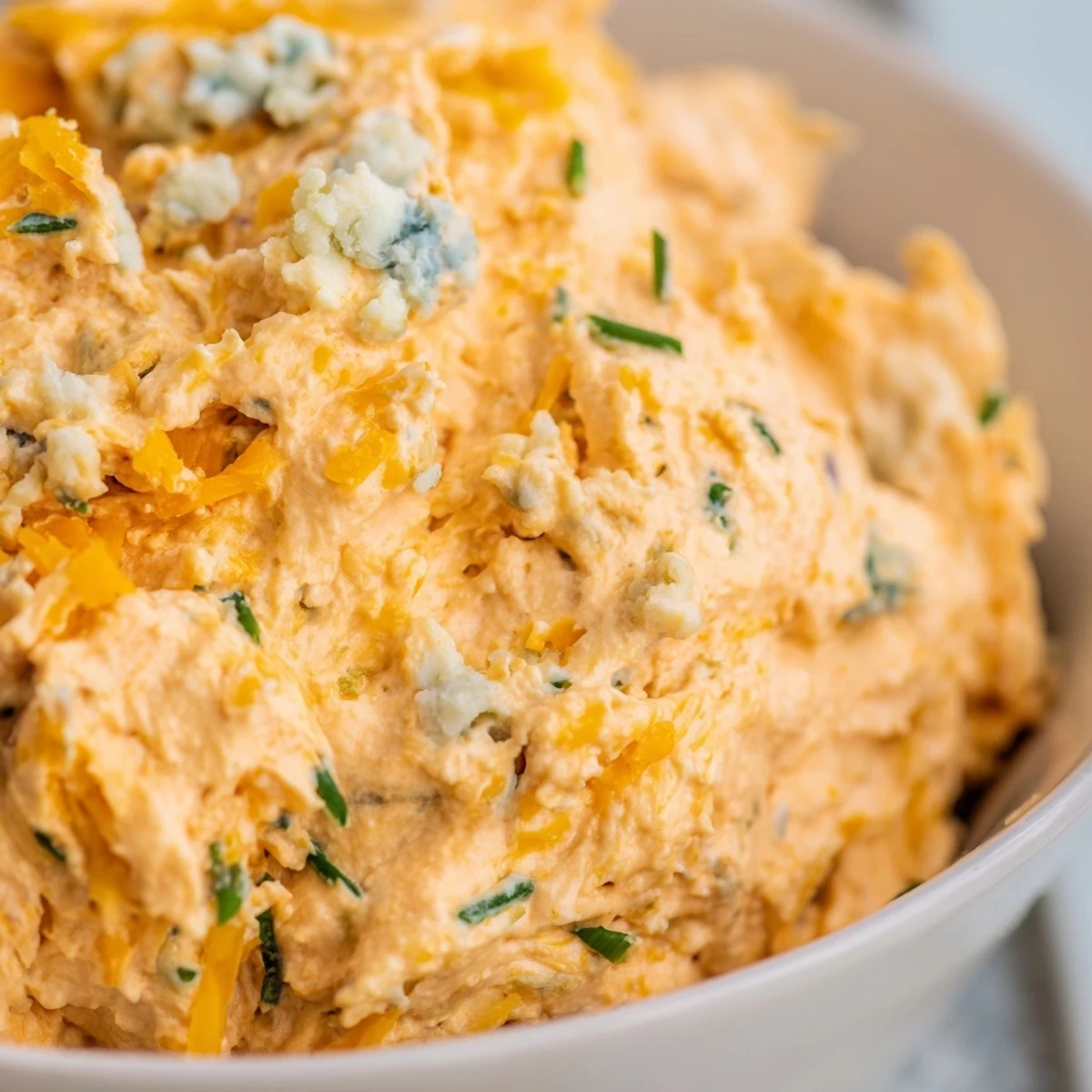 Creamy buffalo pickle dip in a serving bowl surrounded by crunchy chips and fresh veggie sticks for dipping