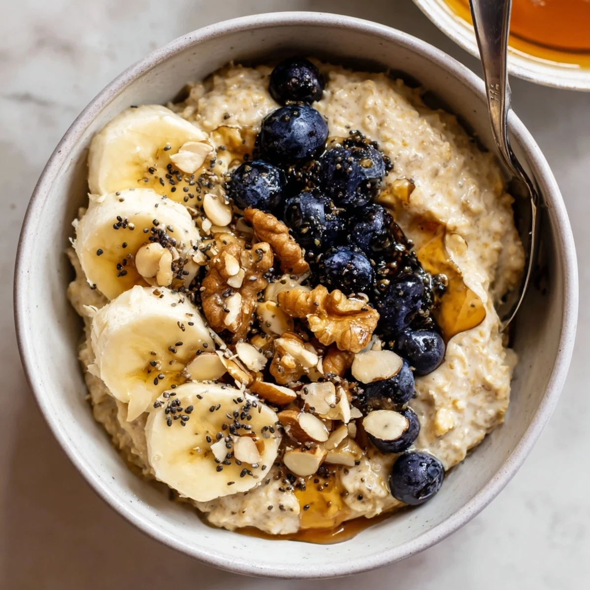 Protein Oatmeal steaming in bowls topped with banana, nuts, and berries