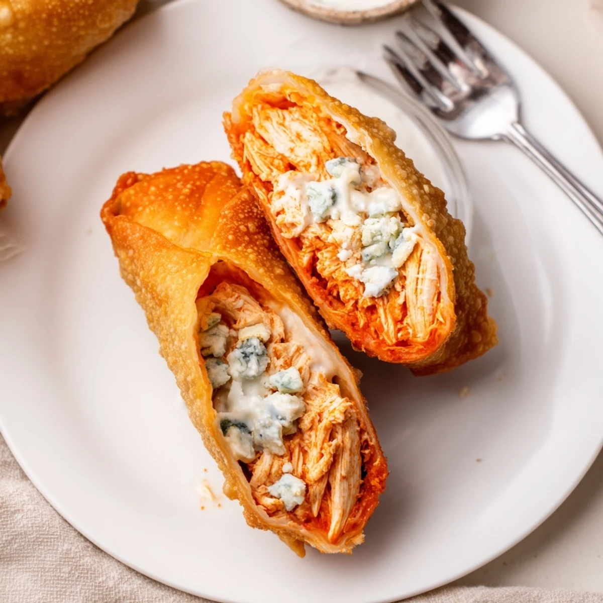 Plate of crunchy Buffalo Chicken Egg Rolls Recipe beside blue cheese and celery.