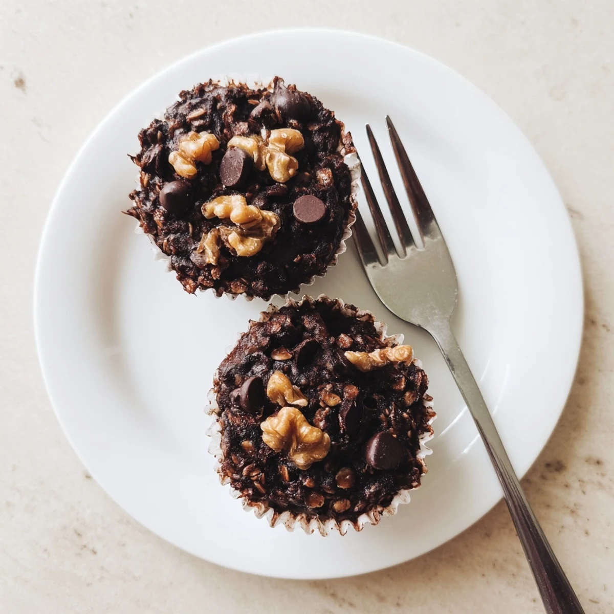 Fudgy dark chocolate oatmeal cupcakes topped with flaky sea salt on a white wire cooling rack
