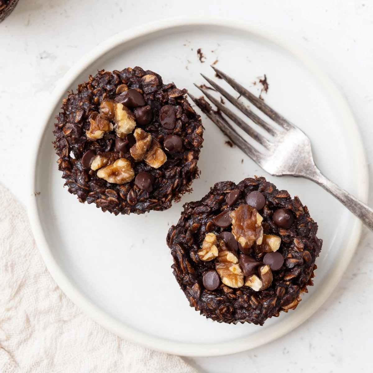 Rich dark chocolate oatmeal muffins bursting with chocolate chips and nuts in a muffin tin