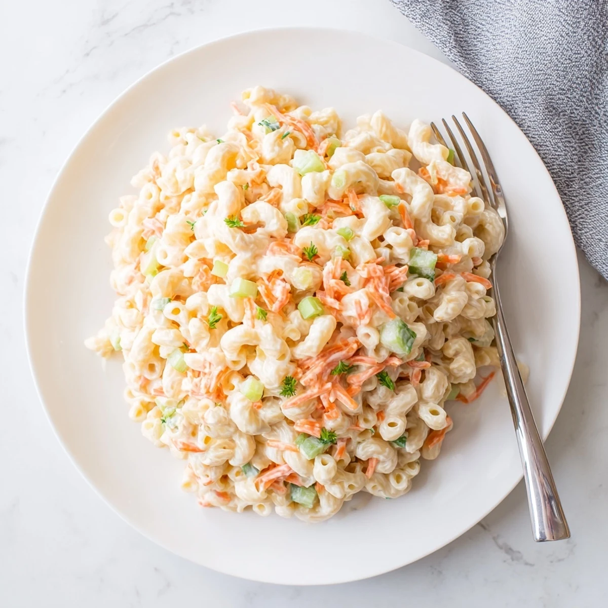 Creamy Hawaiian style mac salad with tender elbow macaroni and colorful grated vegetables in a white serving bowl