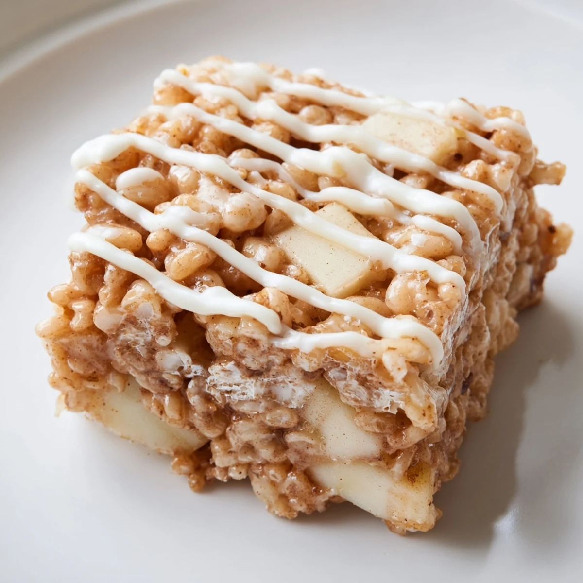 Festive Apple Pie Rice Krispie Treats dessert with diced apples and melted white chocolate atop crispy rice cereal