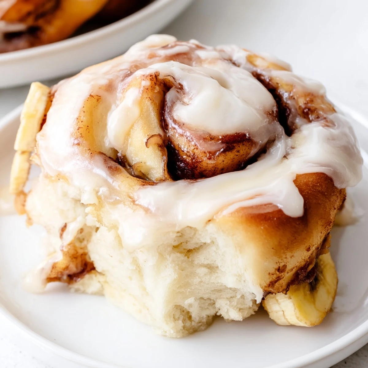 Warm banana cinnamon rolls topped with creamy white glaze and served for a decadent breakfast