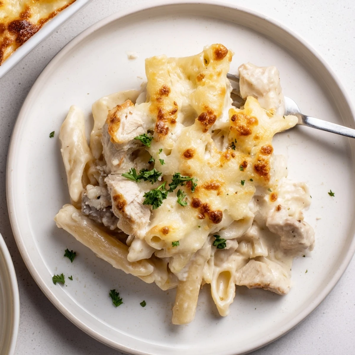 Fork lifting creamy strands from Creamy Chicken Alfredo Bake With Mozzarella Crust