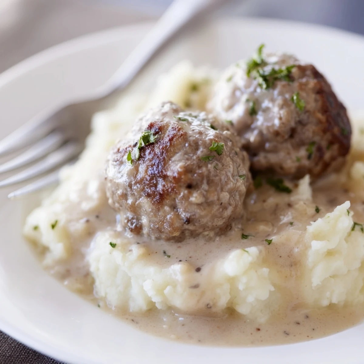 Plate of Crockpot Meatballs Gravy served over buttered noodles, spoonful dripping.