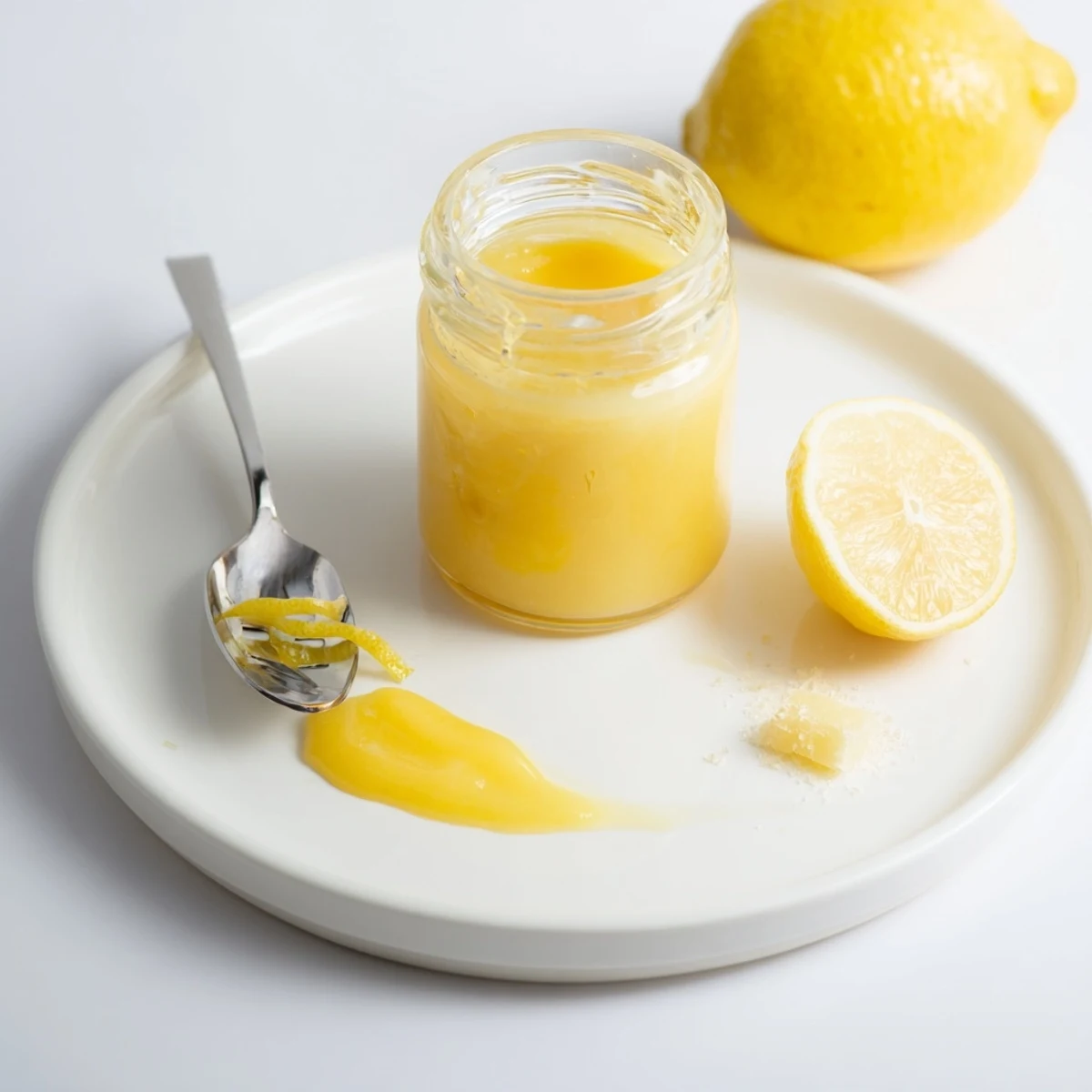 Homemade Lemon Curd glistening in jar, velvety, tangy spread for scones.