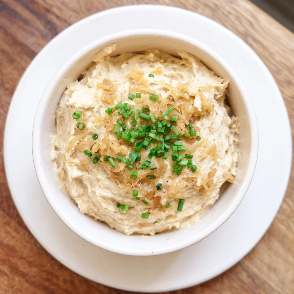 Rich homemade French onion dip with golden brown caramelized onions served alongside crispy potato chips for party snacking