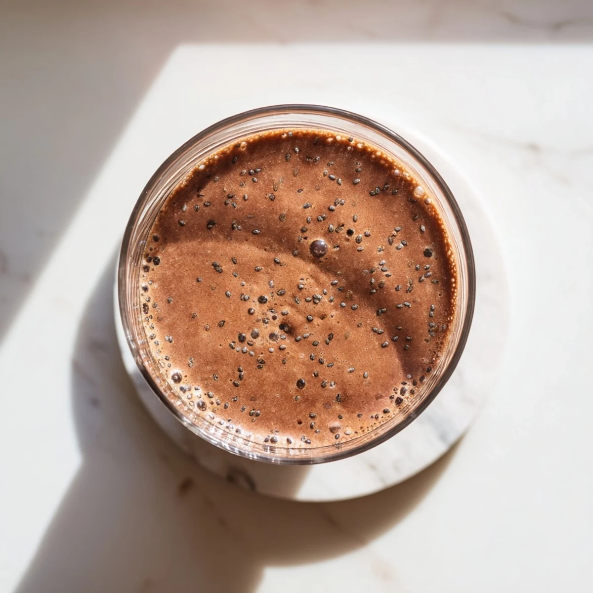 Thick vegan raw chocolate banana shake blending frozen bananas with raw cacao powder and plant-based milk