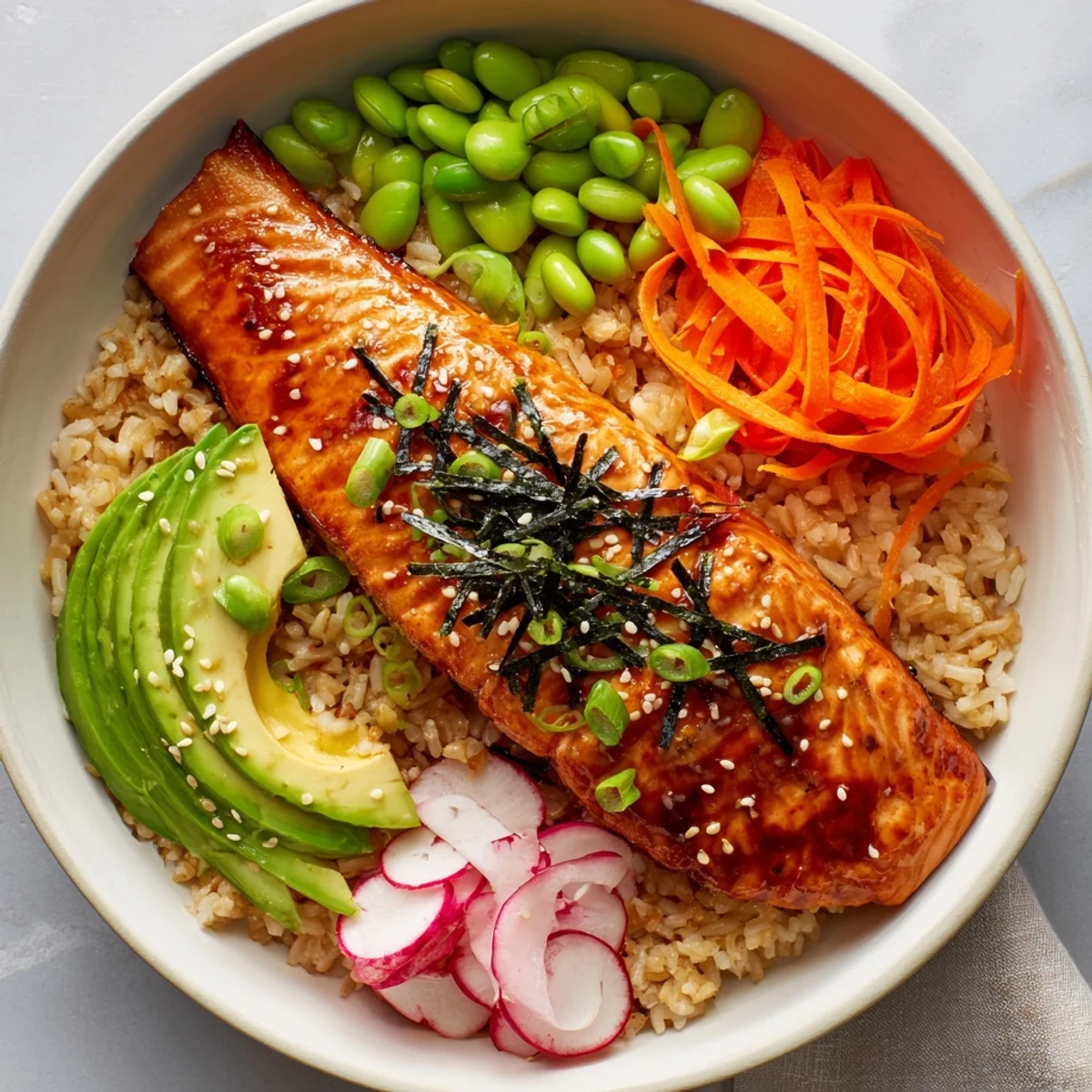Miso salmon grain bowl drizzled with tangy dressing and sprinkled with toasted sesame seeds