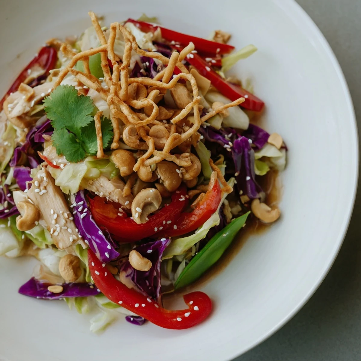 Fresh chicken cashew crunch salad garnished with wonton strips cilantro and sesame seeds