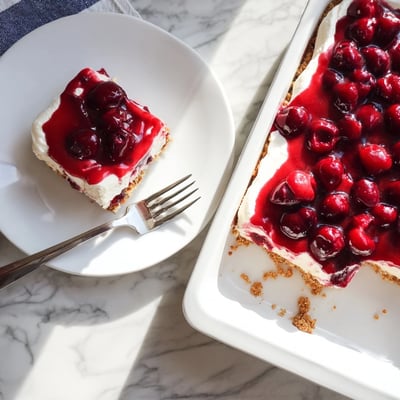 Classic Cherry Delight dessert served on a white plate with a dollop of whipped cream for a festive party treat.