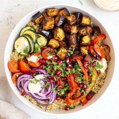 Warm eggplant grain bowl served in a rustic dish with fresh herbs