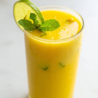 Creamy golden mango cucumber smoothie poured into two mason jars with striped straws